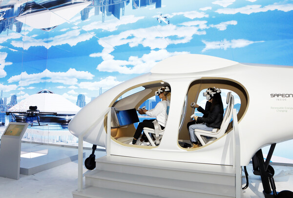 5일 미국 라스베이거스에서 개막하는 최대 가전 , IT 박람회 ‘CES 2023’의 SK그룹관을 사전 방문한 관람객들이 SK텔레콤의 도심항공교통(UAM) 모형에 탑승해 운행 체험을 하고 있다.
